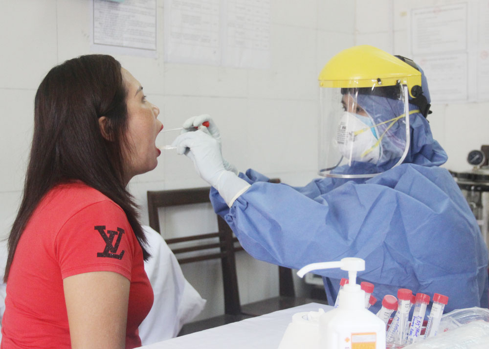 Cán bộ Trung tâm Kiểm soát bệnh tật tỉnh lấy mẫu xét nghiệm Covid-19 cho người về từ vùng có dịch.
