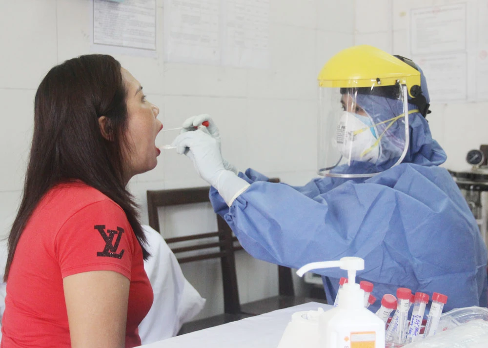 Cán bộ Trung tâm Kiểm soát bệnh tật tỉnh lấy mẫu xét nghiệm Covid-19 cho người về từ vùng có dịch.