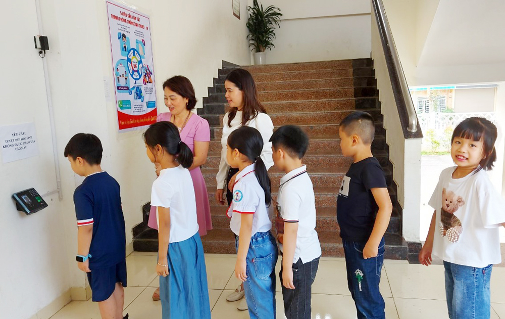 Học sinh Trường Tiểu học Nguyễn Du điểm danh bằng máy tự động khi đến lớp học.