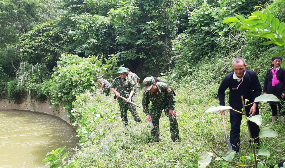 Hội viên nông dân và bộ đội biên phòng tham gia phát dọn, vệ sinh khu vực biên giới.