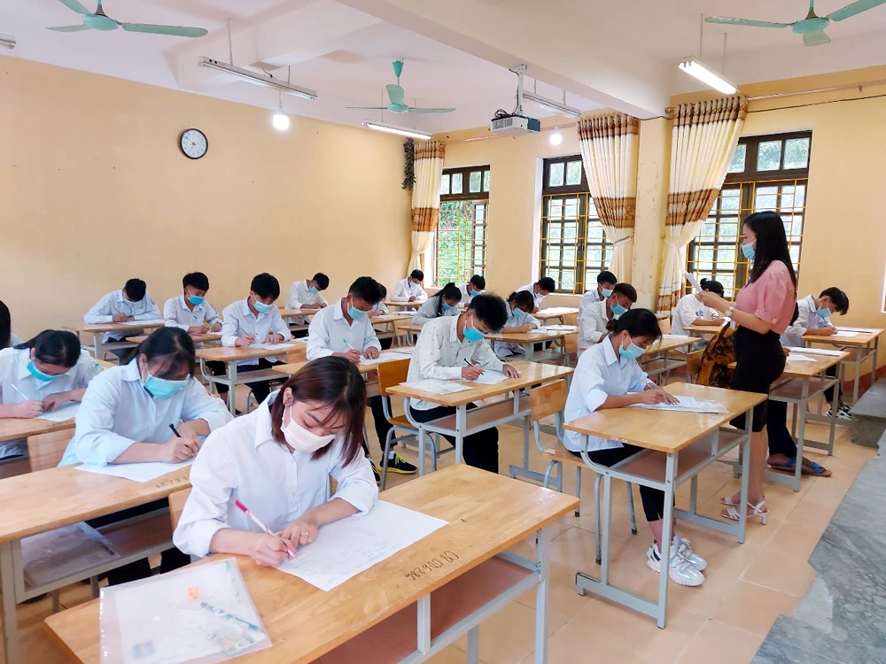 Giám thị hướng dẫn thí sinh điền thông tin vào tờ giấy thi.