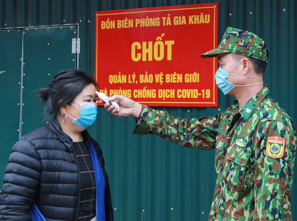 Kiểm tra thân nhiệt cho người dân trở về từ bên kia biên giới.