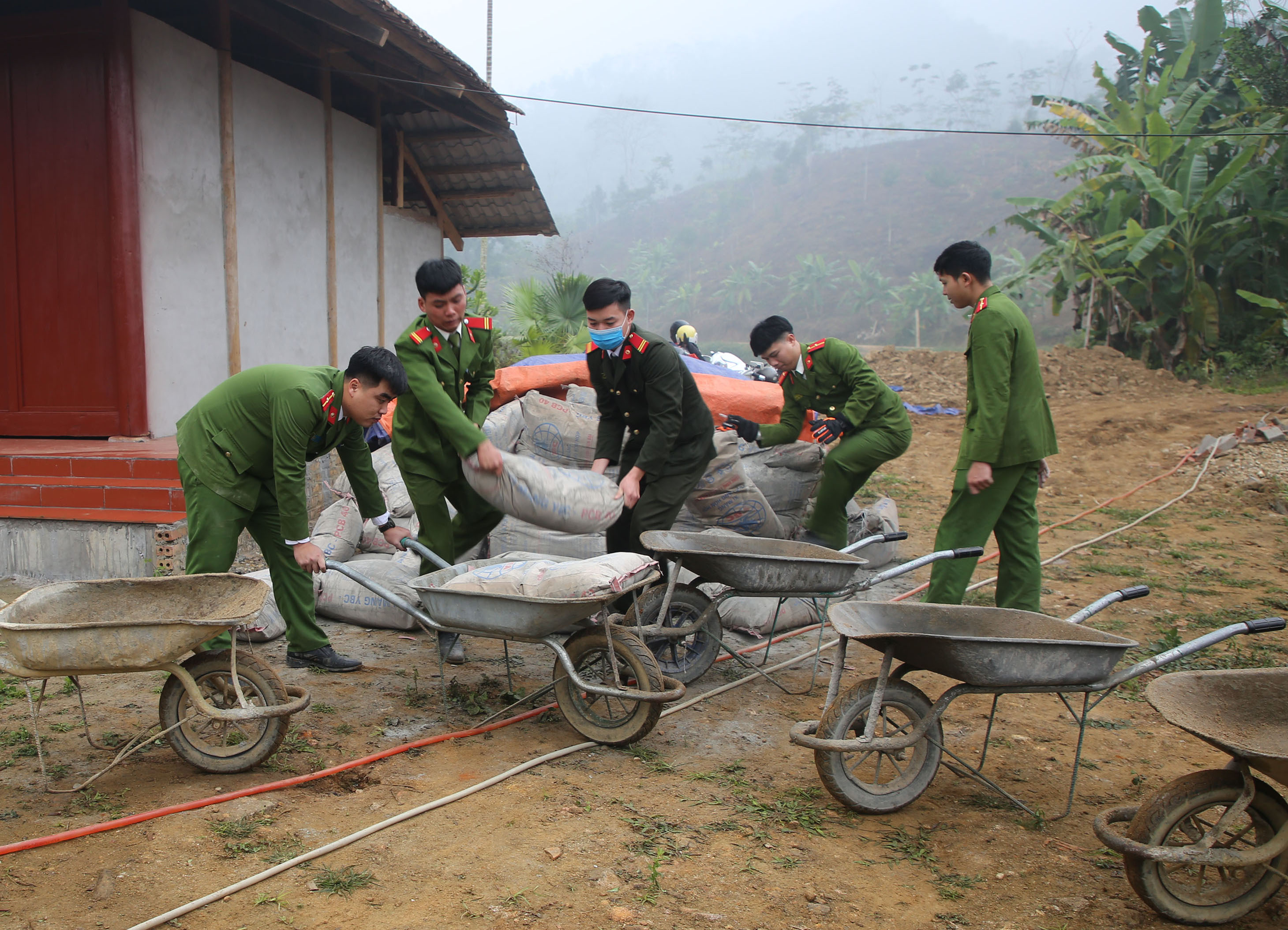 Cán bộ, chiến sỹ Công an huyện Bảo Yên giúp dân vận chuyển vật liệu làm đường.