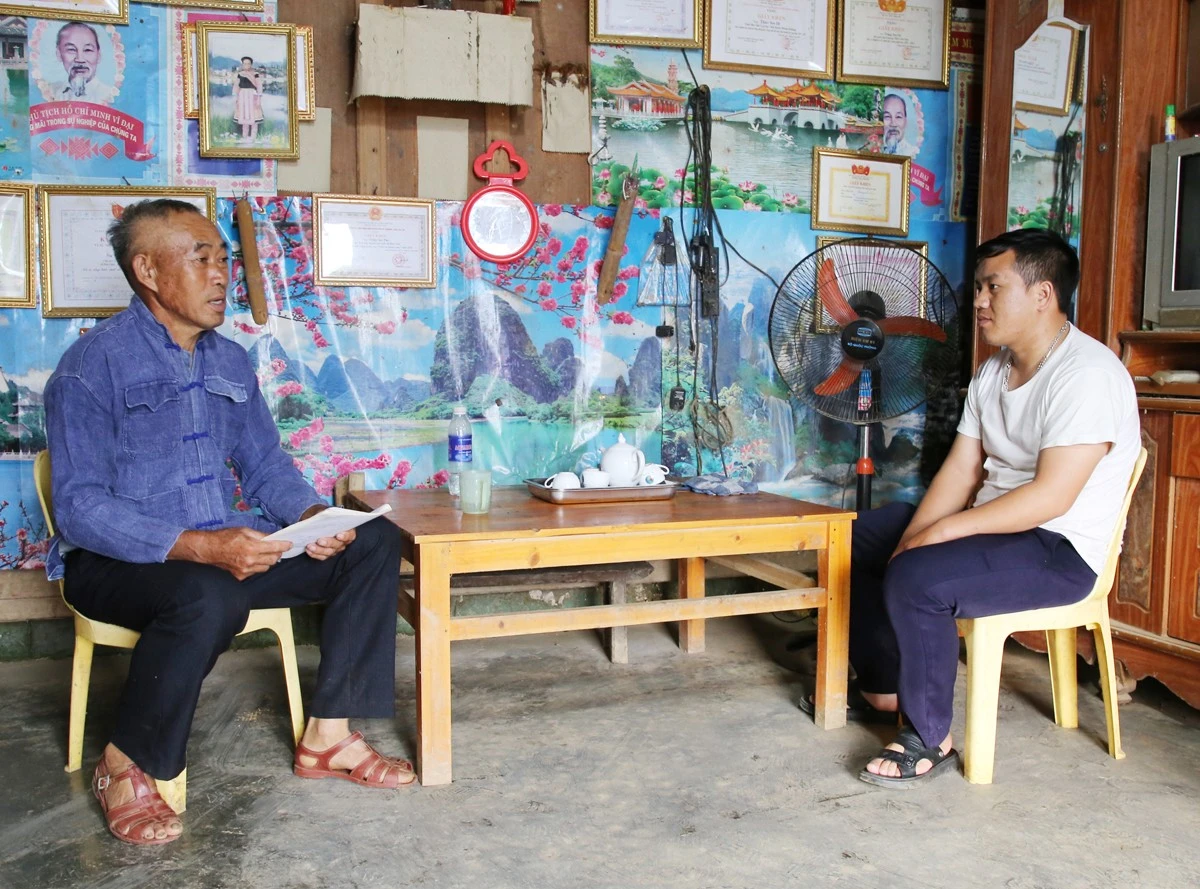Ông Tráng Seo Pao (trái ảnh) tuyên truyền về phát triển kinh tế cho người dân trong thôn.