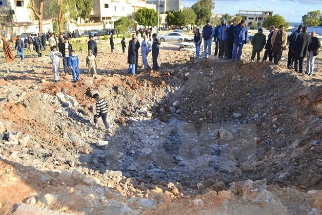 Người dân Libya vây quanh một hố bom sau cuộc không kích các mục tiêu IS tại Derna, cách thủ đô Tripoli, Libya khoảng 100km ngày 7/2 vừa qua.