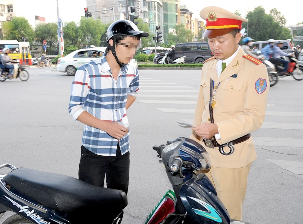 Với công nghệ làm giả giấy tờ hiện đại, tinh vi, rất khó xác định người điều khiển phương tiện dùng GPLX thật hay giả (Trong ảnh: CSGT Hà Nội kiểm tra GPLX người điều khiển phương tiện trên phố Nguyễn Văn Huyên). Ảnh: K.Linh