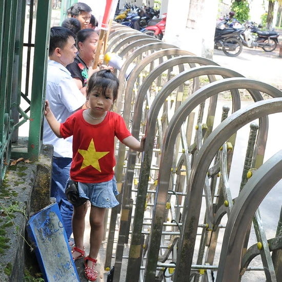 Bà Hoàng Thị Huệ (quần áo trắng) - người cầm đầu đoàn người. Cháu bé đi theo đoàn tranh thủ chạy nhảy bên cổng.