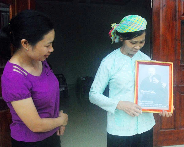 Cháu, chắt (áo tím) nâng niu bức ảnh Bác Hồ chụp với ông Trần Văn Nỏ năm 1958.
