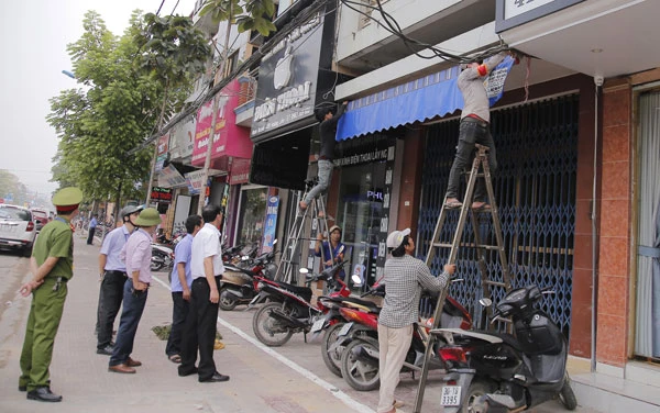 Cán bộ phường Kim Tân hỗ trợ nhân dân tháo dỡ mái hiên di động lấn chiếm vỉa hè.