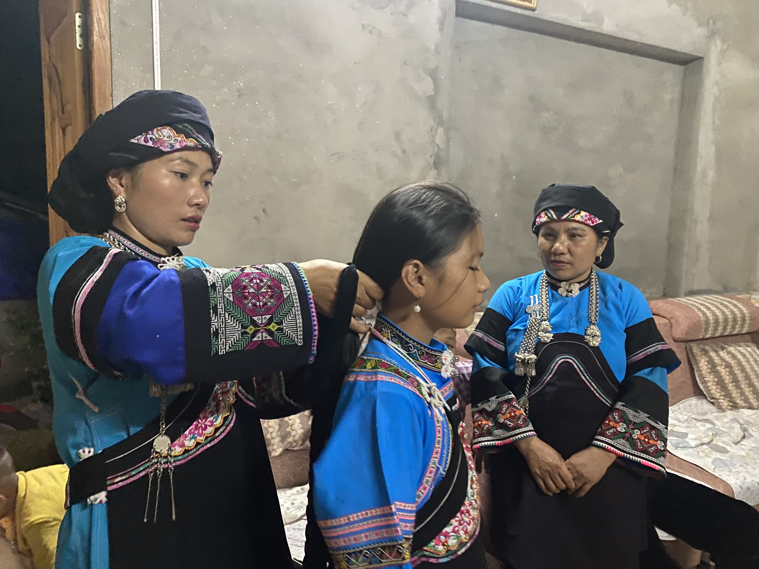 Những người lớn tuổi trong Câu lạc bộ hướng dẫn các em nhỏ cách mặc trang phục truyền thống của người Bố Y.