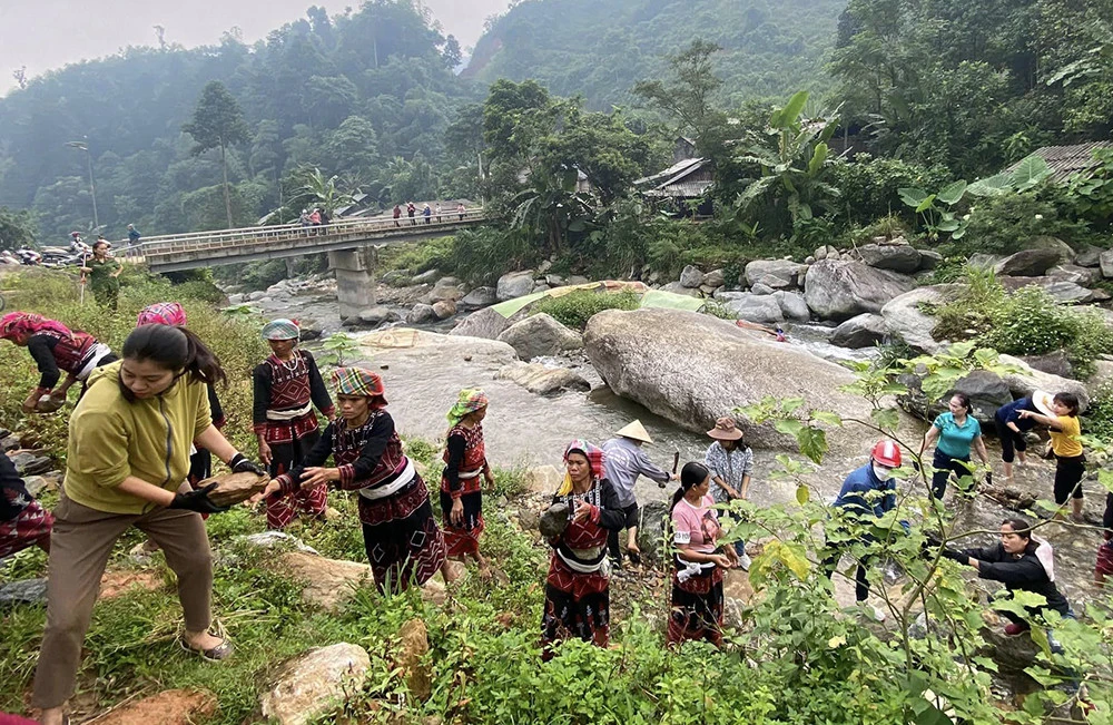 Hội viên phụ nữ vận chuyển đá để kè sân điểm sinh hoạt cộng đồng.