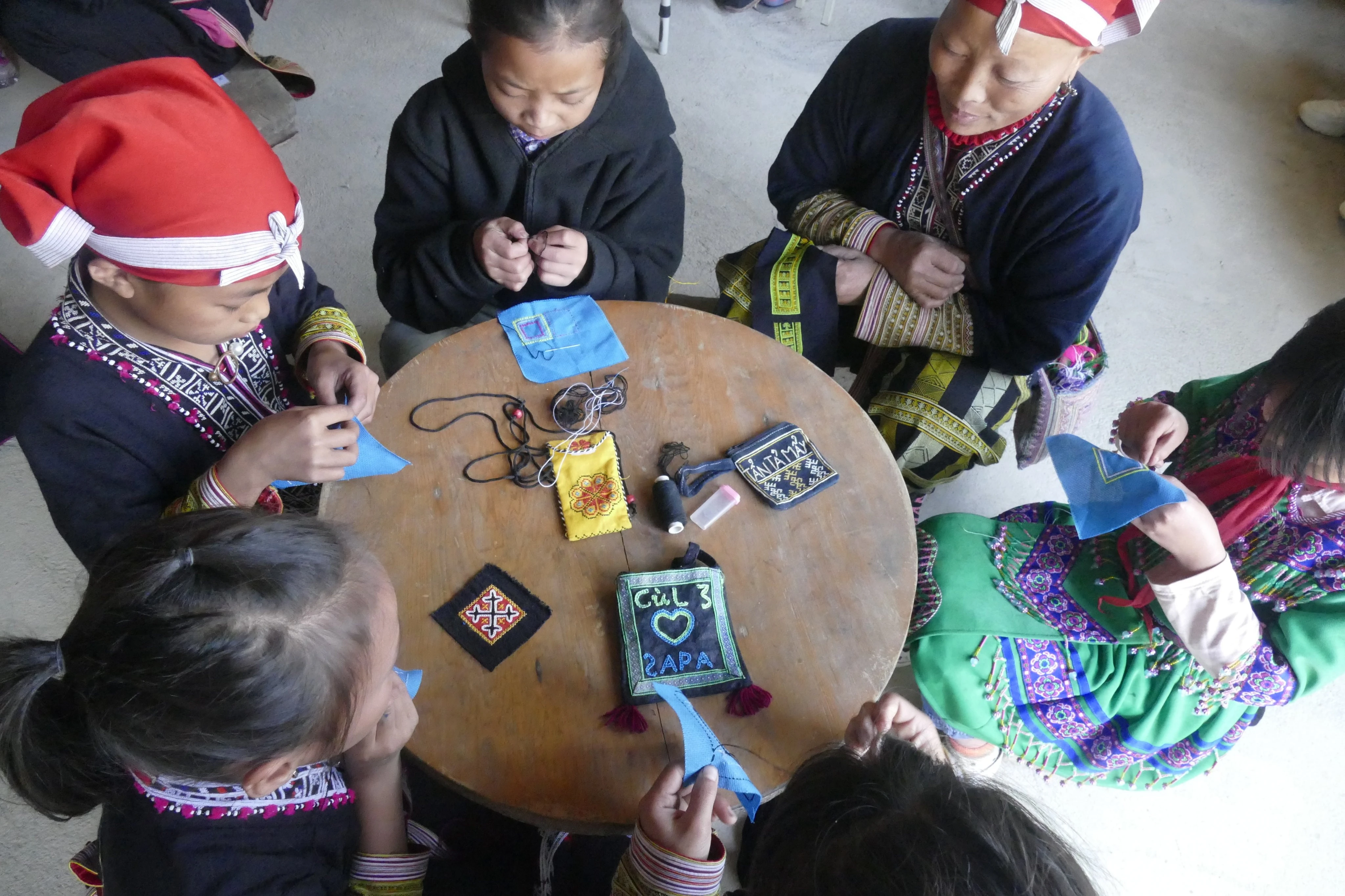 Tranh thủ lúc nông nhàn, người Dao đỏ cùng nhau thêu thổ cẩm để làm các sản phẩm như túi đeo, đệm ngồi.