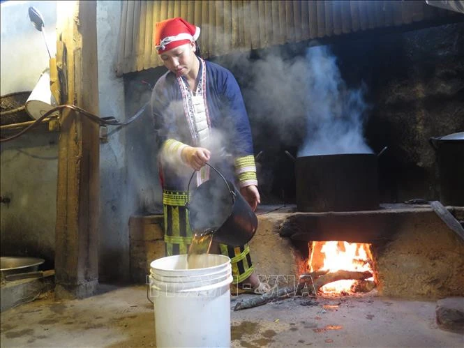 Phụ nữ người Dao đỏ pha nước tắm cho khách.