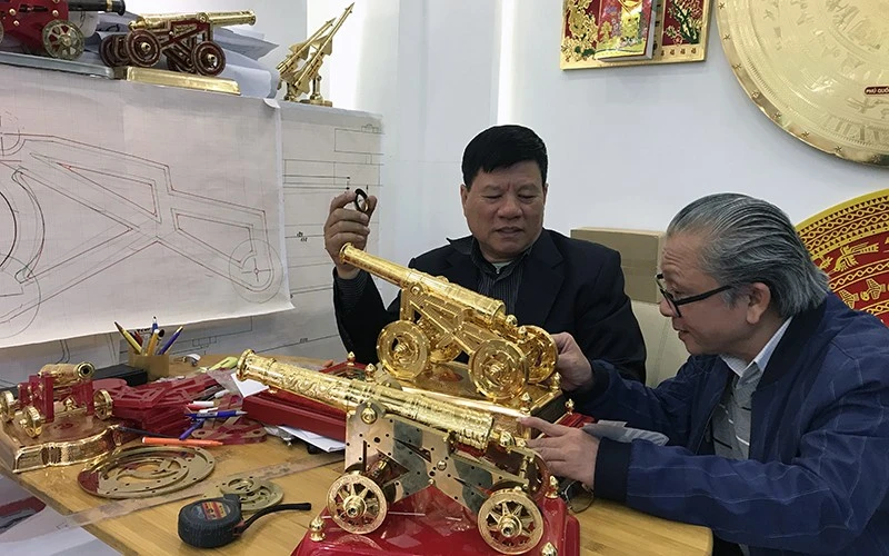 Anh Nguyễn Hồng Phong (bên trái) trao đổi về mô hình súng thần công.