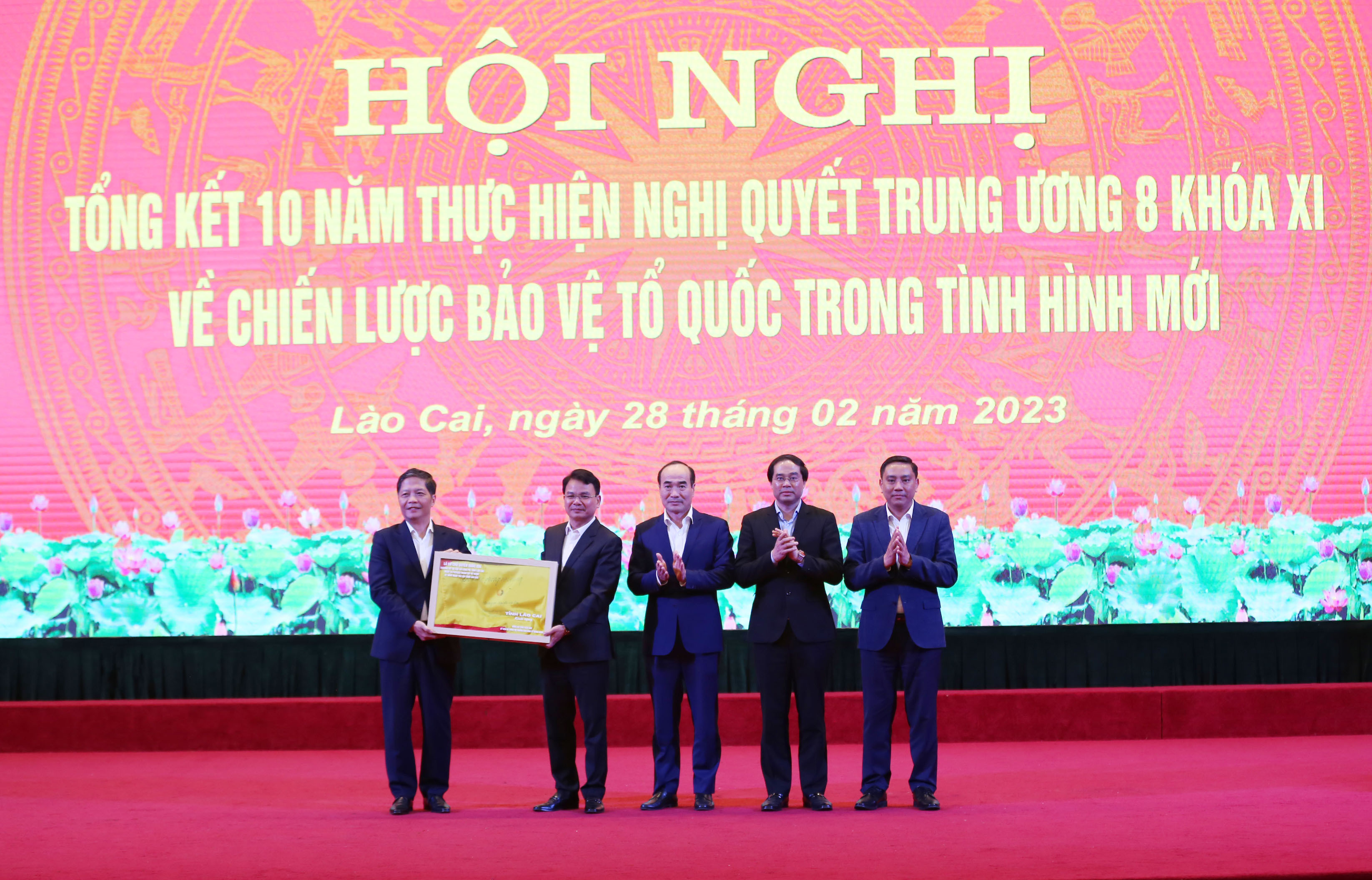 Các đồng chí Thường trực Tỉnh ủy Lào Cai trao tặng lá cờ Tổ quốc cho Trưởng Ban Kinh tế Trung ương Trần Tuấn Anh. Trưởng Ban Kinh tế Trung ương Trần Tuấn Anh trao tặng tỉnh Lào Cai bức ảnh phong cảnh.