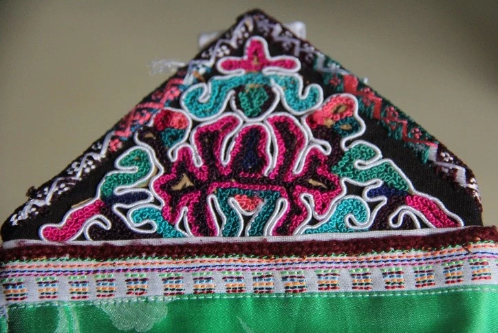 Miếng vải làm đai buộc dây trên tạp dề có thêu hoa văn hình con rồng.