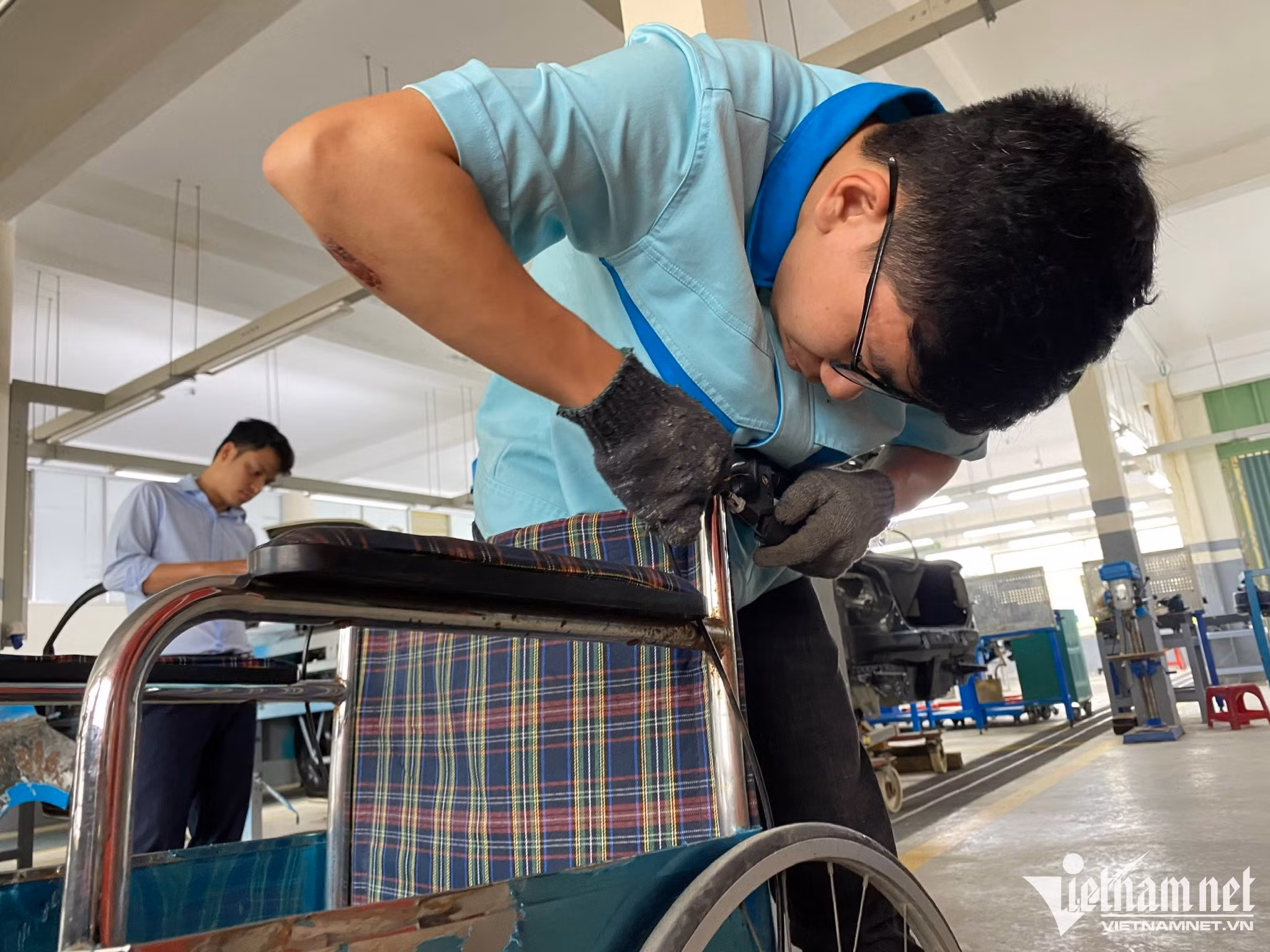 Sinh viên Nguyễn Hồng Quân sửa lại chiếc xe lăn bị hư của người khuyết tật mang đến.