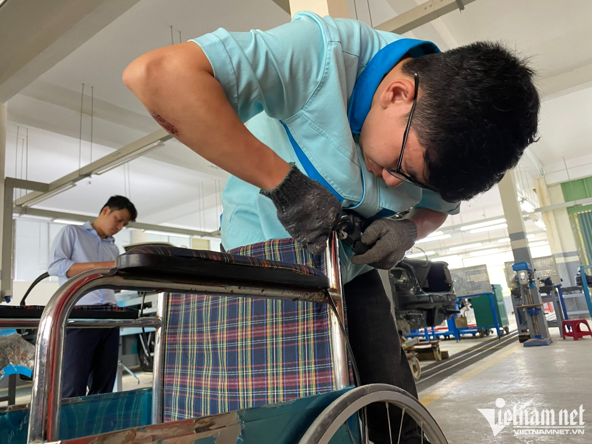 Sinh viên Nguyễn Hồng Quân sửa lại chiếc xe lăn bị hư của người khuyết tật mang đến.