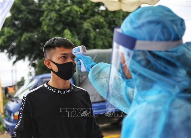 Kiểm tra thân nhiệt cho người dân khu vực cách ly COVID-19.