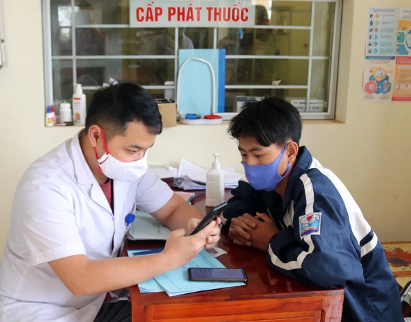 Cán bộ Trạm Y tế xã Hoàng Thu Phố, huyện Bắc Hà hướng dẫn học sinh khai báo y tế qua phần mềm điện tử. Ảnh: Phương Thảo