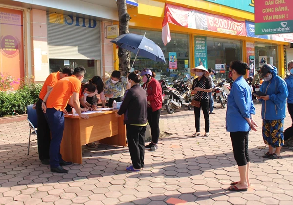 Người dân xếp hàng nhận nhu yếu phẩm.