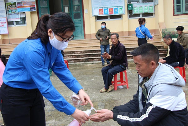 Đoàn viên phát khẩu trang và hướng dẫn người dân sát khuẩn tay.