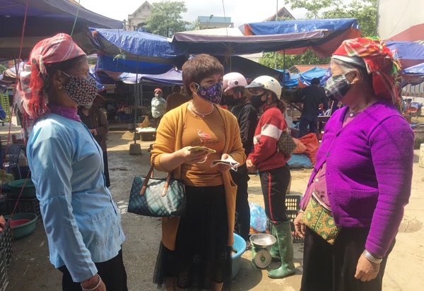 Cô Hạnh tặng khẩu trang vải cho tiểu thương ở chợ Văn Bàn.