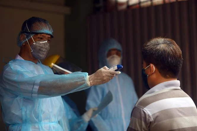 Đo thân nhiệt cho người dân phòng dịch COVID-19. Ảnh: TTXVN