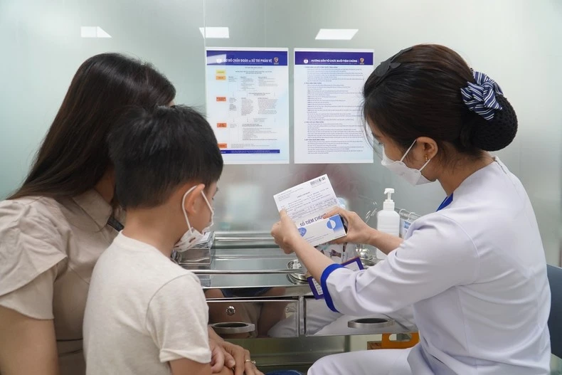 Nhân viên tiêm chủng rà soát lại thông tin người tiêm, loại vaccine, hạn sử dụng cho mẹ của trẻ.