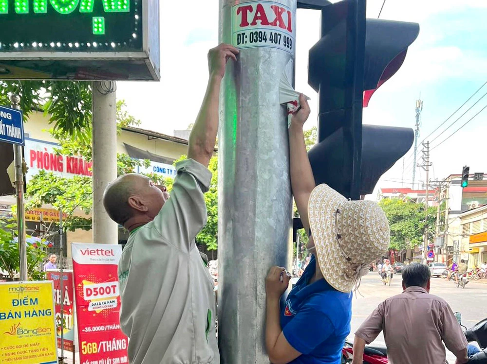 Bóc gỡ biển quảng cáo, rao vặt sai quy định trên các tuyến phố chính.jpg