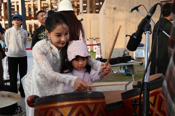 Một "du khách nhí" thích thú thử nhạc cụ của Việt Nam.