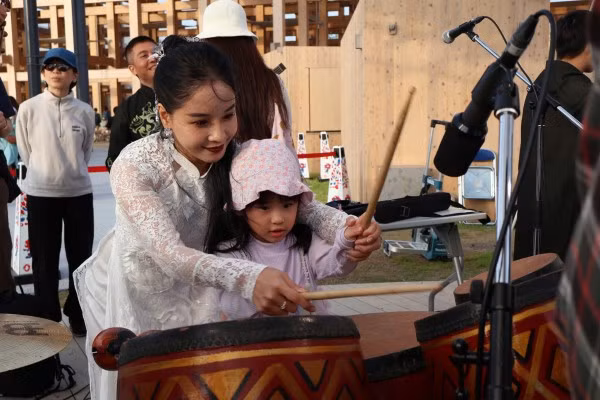 Một "du khách nhí" thích thú thử nhạc cụ của Việt Nam.