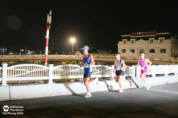 Top ba runner nam dẫn đầu cự ly full marathon (từ trái qua) Hứa Thuận Long, Bùi Văn Dũng và Kento Kabashima ở đoạn lên cầu khoảng km thứ 15. Ảnh: VnExpress Marathon Hải Phòng