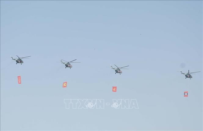 Biên đội máy bay trực thăng mang cờ bay trên bầu trời khu vực tổ chức lễ kỷ niệm.