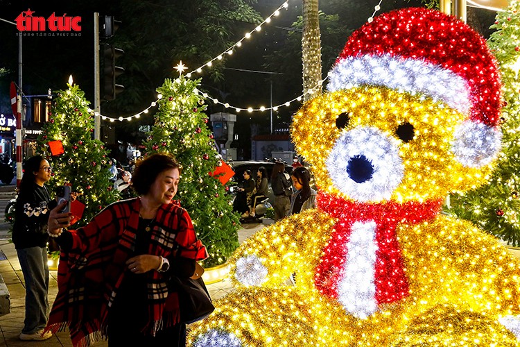 Người dân chụp ảnh lưu niệm bên mô hình gấu Noel và cây thông trang trí tại Vincom Bà Triệu.