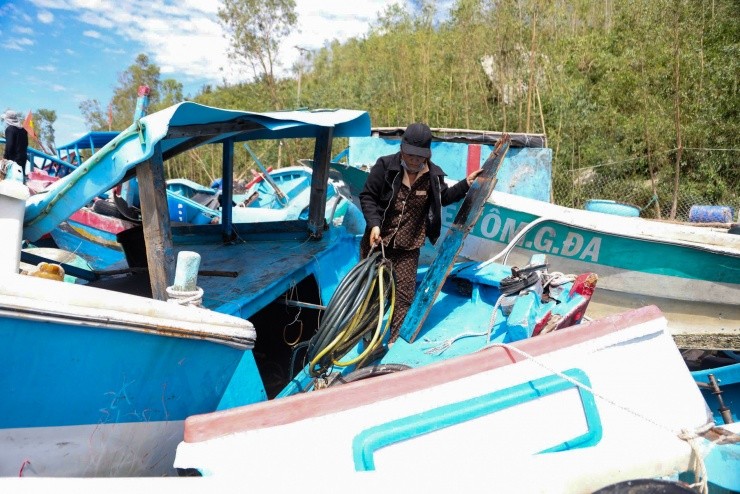 Bà Hợp, 43 tuổi bên chiếc ghe cá trị giá 200 triệu đồng bị sóng đánh dạt vào bờ. "Thân ghe giờ hư hết, tôi chỉ tháo cục máy ra bán lại để gỡ gạc lại tiền vốn", bà Hợp nói.
