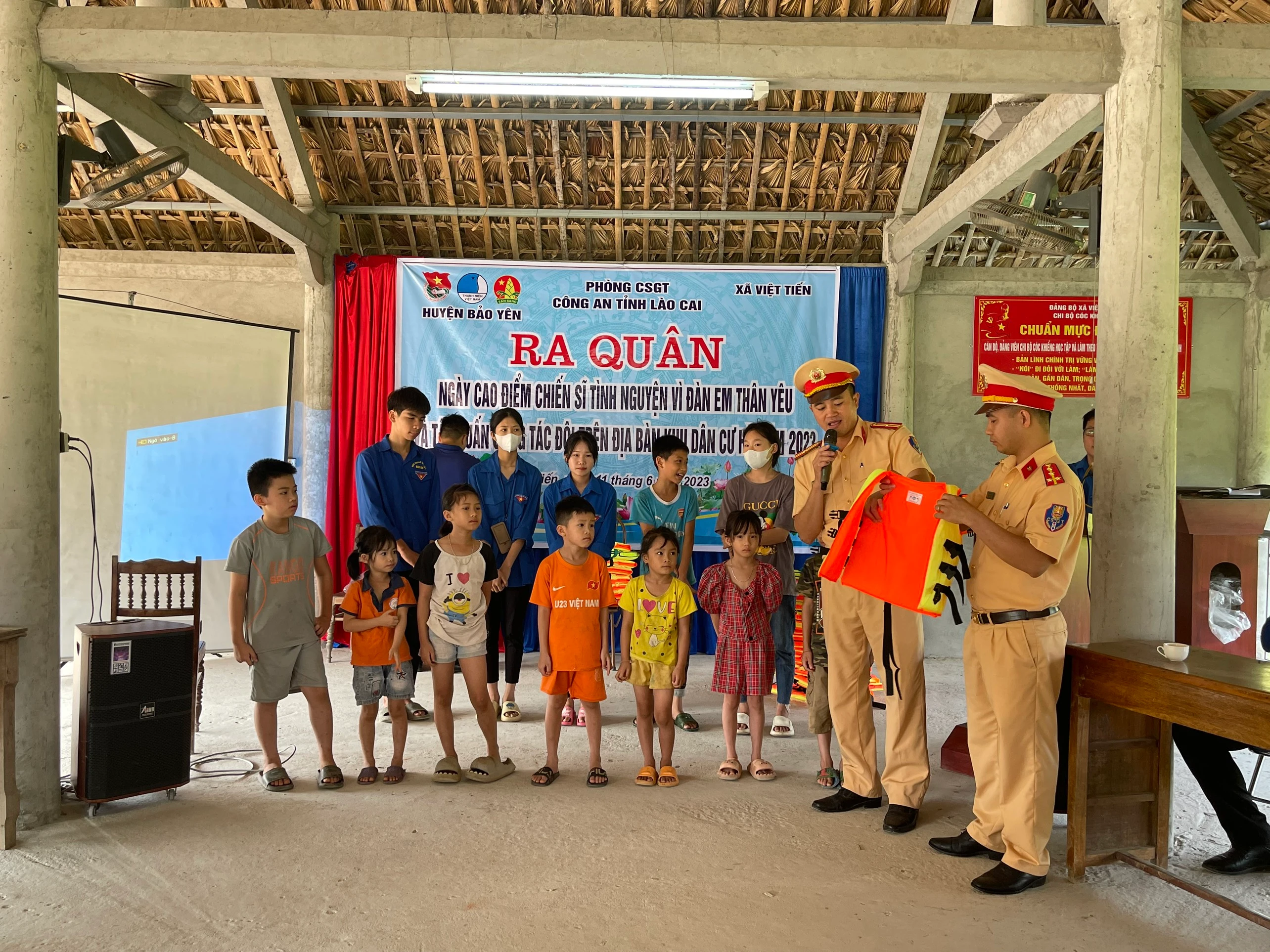Chiến sĩ Phòng Cảnh sát giao thông, Công an tỉnh Lào Cai hướng dẫn cách mặc áo phao cho các em thanh, thiếu niên xã Việt Tiến.jpg
