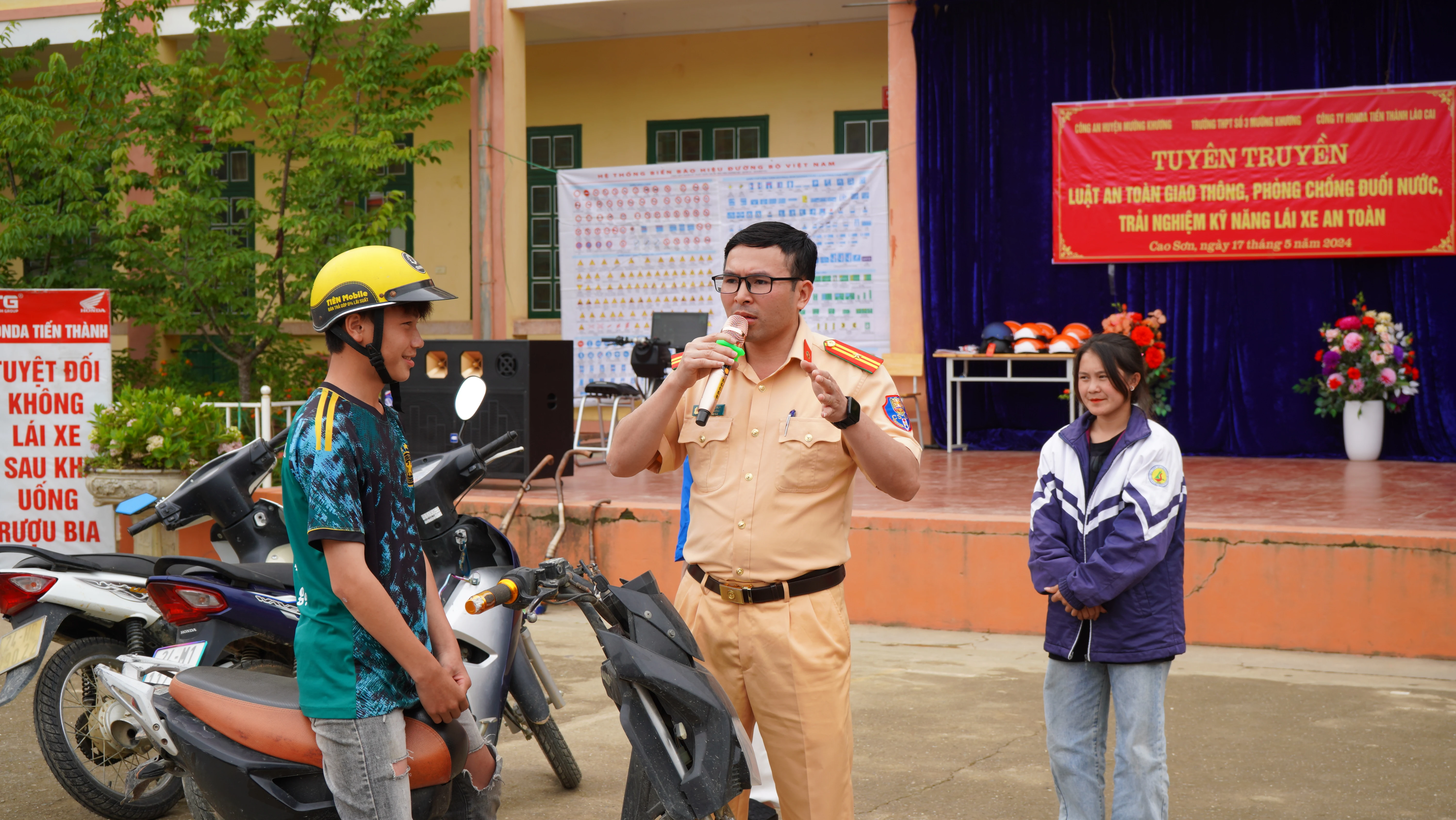 Cán bộ Đội Cảnh sát Giao thông - Trật tự Công an huyện Mường Khương tuyên truyền quy định đối với người ngồi trên xe máy, xe máy điện, xe đạp điện với học sinh .JPG
