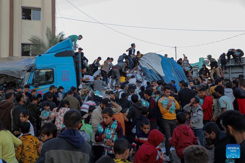 Người dân Palestine lấy nước uống từ xe tải chở thực phẩm ở thành phố Khan Younis phía Nam Dải Gaza, ngày 21/11/2023.