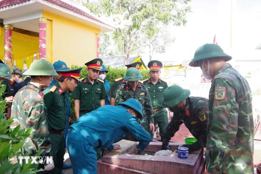 Lực lượng chuyên trách tiến hành khai quật mộ liệt sĩ. (Ảnh: Mai Trang/TTXVN)