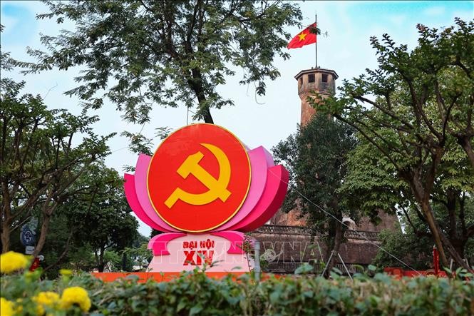 Biểu tượng búa liềm trên đài sen hồng nổi bật trước Cột cờ Hà Nội (khu vực đường Điện Biên Phủ), kết hợp vẻ đẹp lịch sử hào hùng với không khí chính trị trang nghiêm.