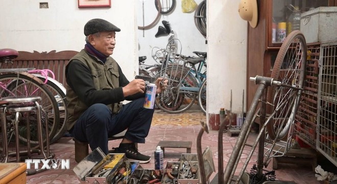 Tự tay ông Lê Trọng Kính sơn lại những bộ phận của xe đạp để chiếc xe sau khi lắp ráp sáng bóng như mới.