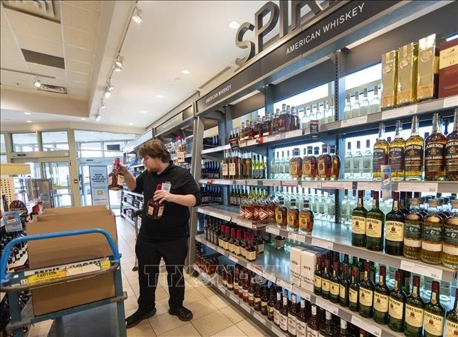 Nhân viên thu hồi những chai rượu sản xuất tại Mỹ trên kệ hàng trong siêu thị ở Oakville, Ontario, Canada.