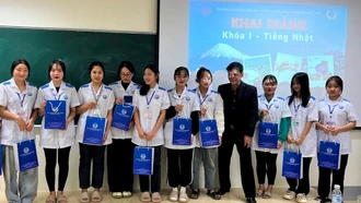 A representative of Bao Viet Trading jo&#105;nt Stock Company hands over Japanese language materials and textbooks to first-year students of the Japanese Language Department at Yen Bai College during the opening cerem&#111;ny. 