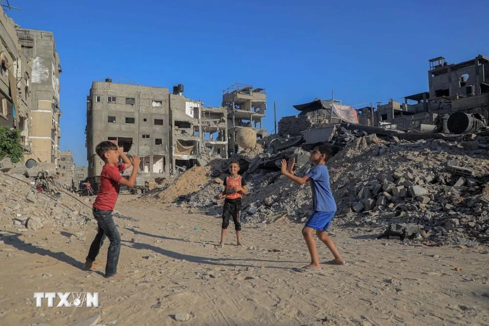 Trẻ em vui chơi bên đống đổ nát của những tòa nhà bị phá hủy do chiến sự tại Dải Gaza ngày 20/8/2024.
