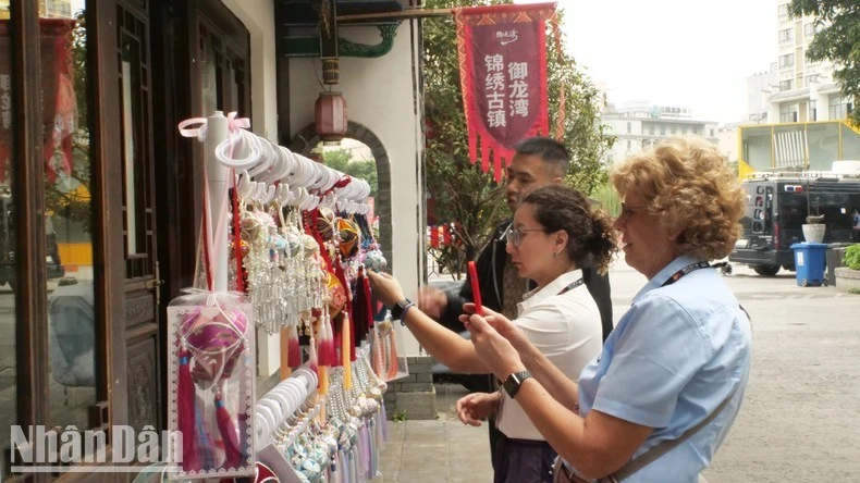 Thành viên của đội đua xe đạp tranh thủ mua quà lưu niệm ở Cẩm Tú cổ trấn - điểm du lịch cấp 4A của Trung Quốc.