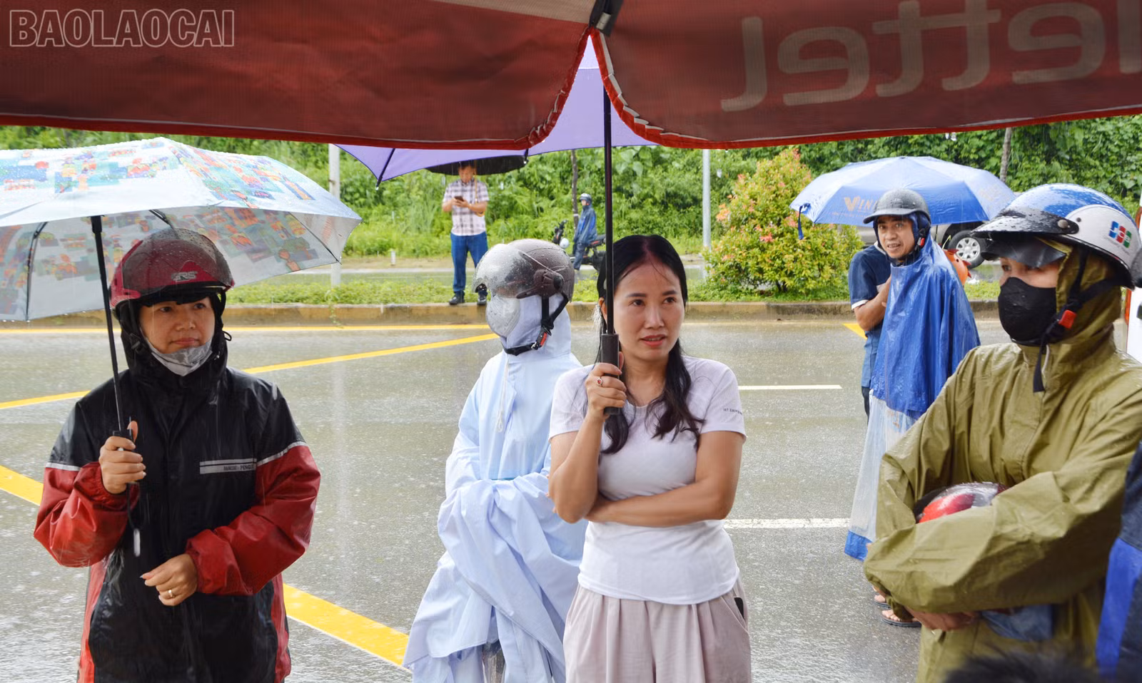 Sau khi đưa thí sinh đến điểm thi an toàn, nhiều phụ huynh đội mưa, nán lại phía ngoài khu vực thi để đợi thí sinh.