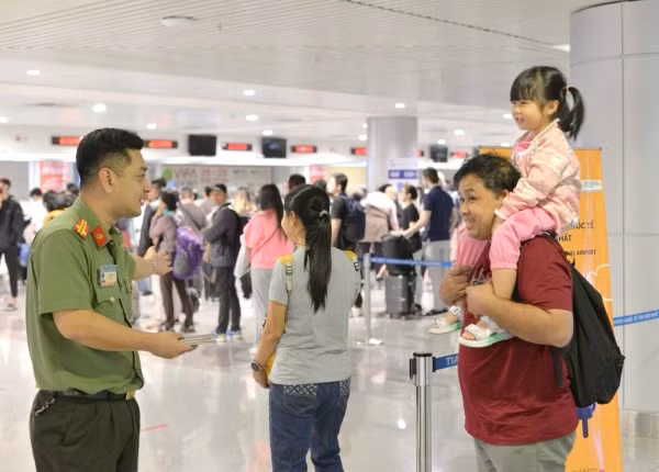 Cán bộ Công an cửa khẩu Cảng hàng không quốc tế Tân Sơn Nhất hướng dẫn người dân làm thủ tục xuất nhập cảnh.