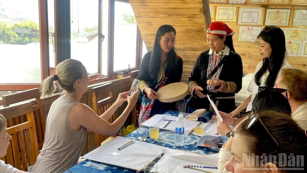 Du khách tìm hiểu kỹ thuật vẽ hoa văn bằng sáp ong và nhuộm chàm tại bản Tả Van. (Ảnh: NGỌC LIÊN)