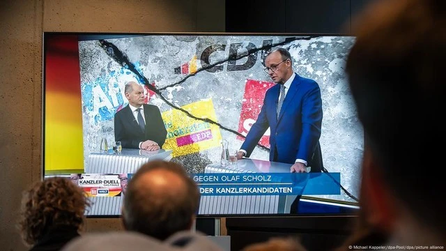 Người dân xem cuộc tranh luận giữa hai ứng viên Olaf Scholz (trái) và Friedrich Merz được phát trên truyền hình hôm 19-2.